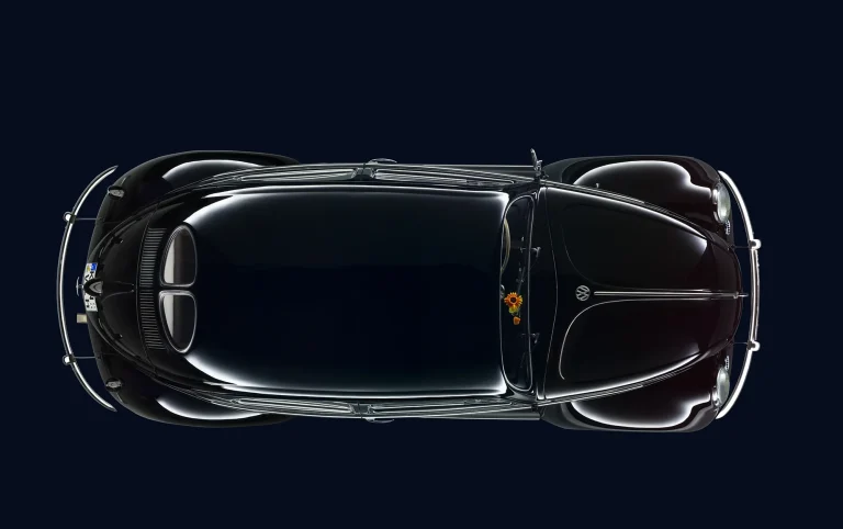 VW Käfer Studioaufnahme in Draufsicht – Klassische Automobilfotografie Schwarzer Volkswagen Käfer in der Draufsicht auf dunkelblauem Hintergrund mit verchromten Details und charakteristischer Karosserieform.