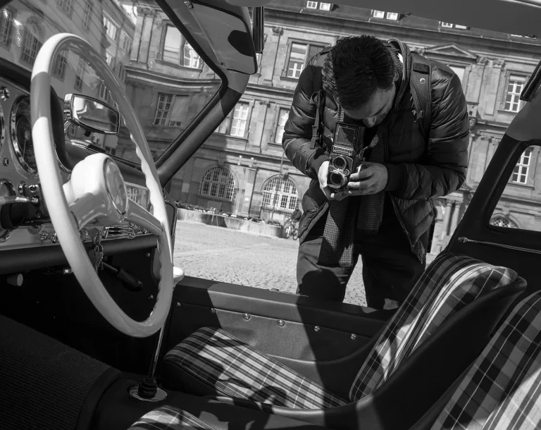 Oldtimer trifft analoge Fotografie Fotograf mit analoger Kamera fotografiert den Innenraum eines Mercedes-Benz 300 SL Flügeltürers in Schwarz-Weiß.